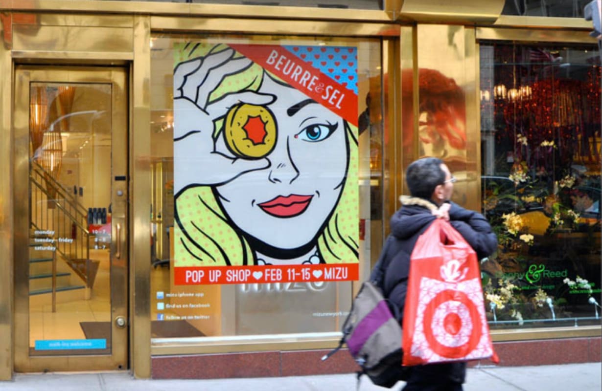 Printed window graphic of a cartoon woman drawn in a retro style, who appears to be looking at a pedestrian.